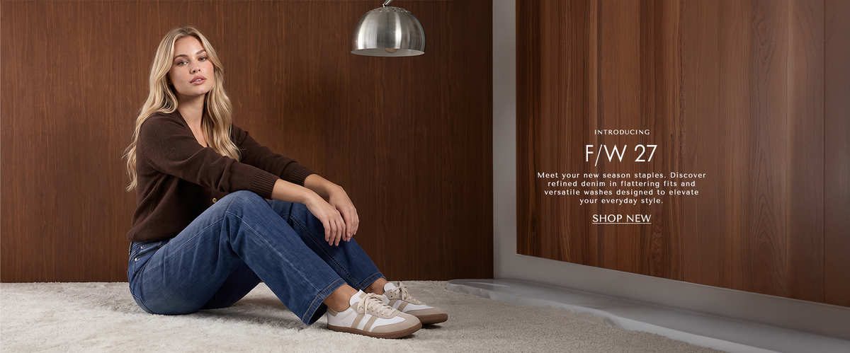 A model sitting on the carpet wearing long sleeve brown cardigan with light blue jeans and sneakers. Text below reading ' Introducing: F/W 27 Meet your new season staples. Discover refined denim in flattering fits and versatile washes designed to elevate your everyday style. CTA 'Shop New'